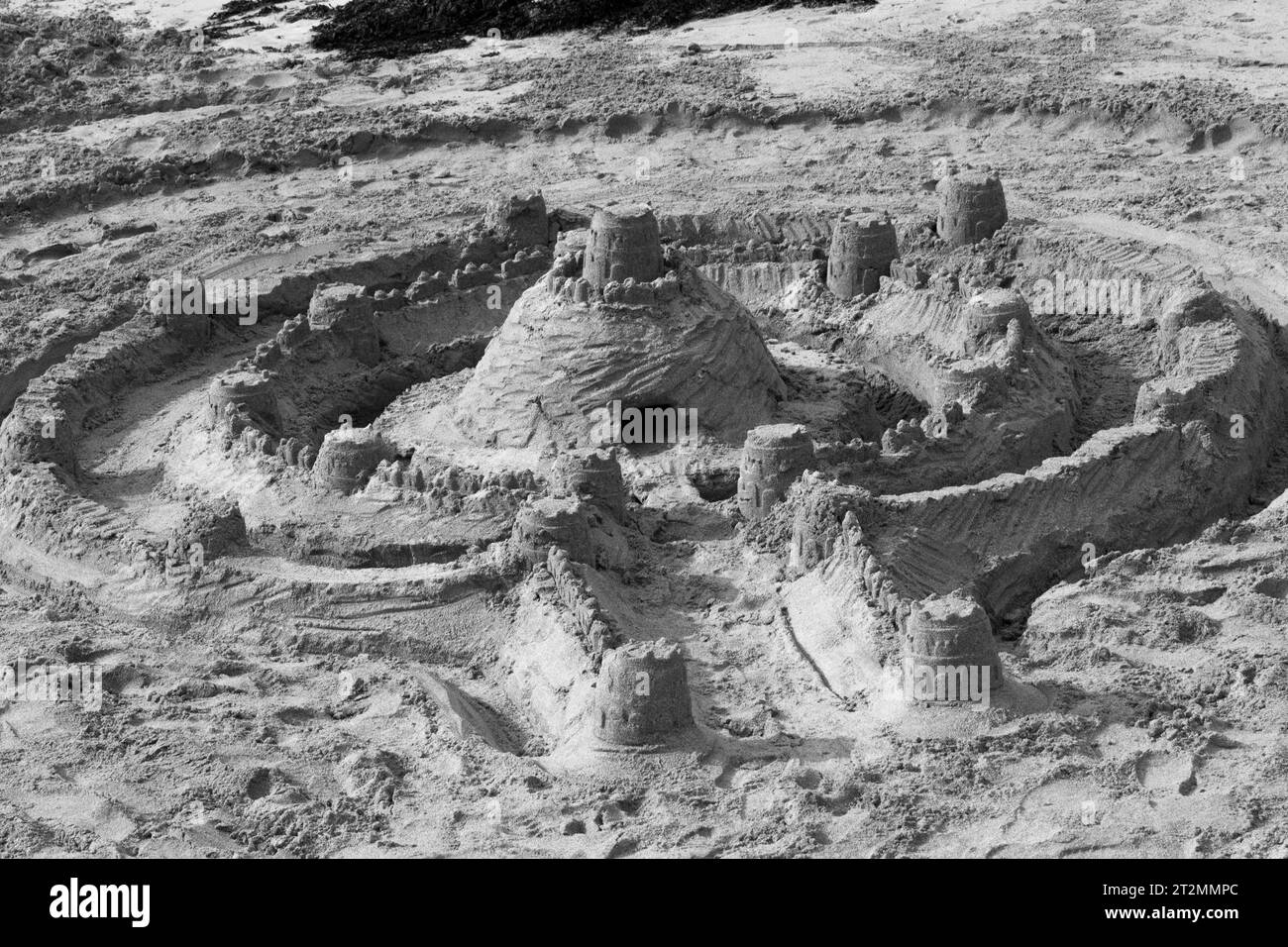 Château de sable désert sur la plage séchant au soleil. Un travail d'heures d'enfance mais de plaisir éphémère. Destiné à être emporté. Monochrome Banque D'Images