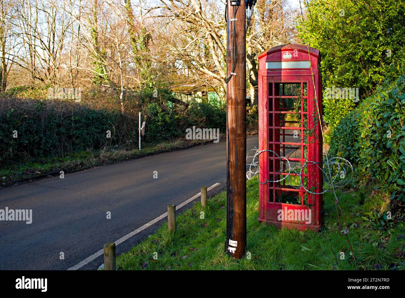 Une cabine téléphonique K6 désaffectée entourée de fil de rasoir sur une route rurale dans le Kent, au Royaume-Uni Banque D'Images