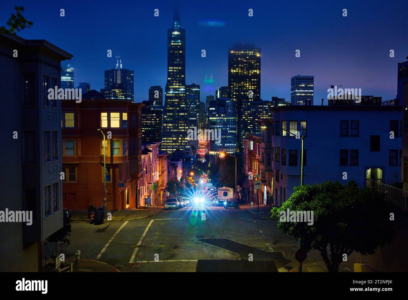 Des lumières de voiture brillantes remontent la colline de la nuit brumeuse au-dessus des gratte-ciel du centre-ville de San Francisco Banque D'Images
