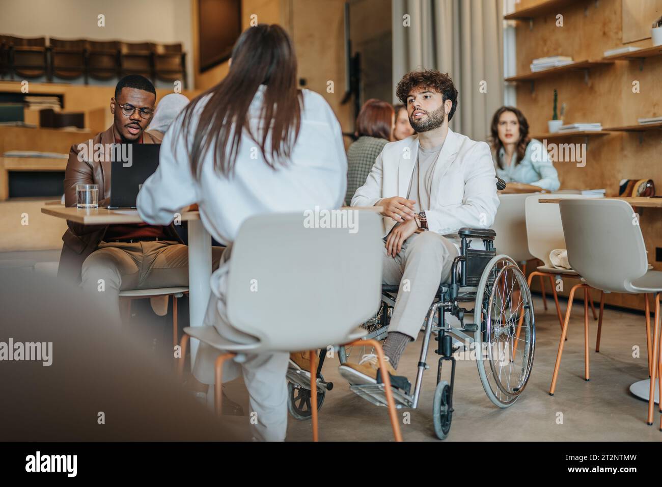 Portrait de l'homme moderne à l'aide d'un ordinateur portable au bureau moderne. Une personne handicapée en fauteuil roulant travaille au bureau Banque D'Images