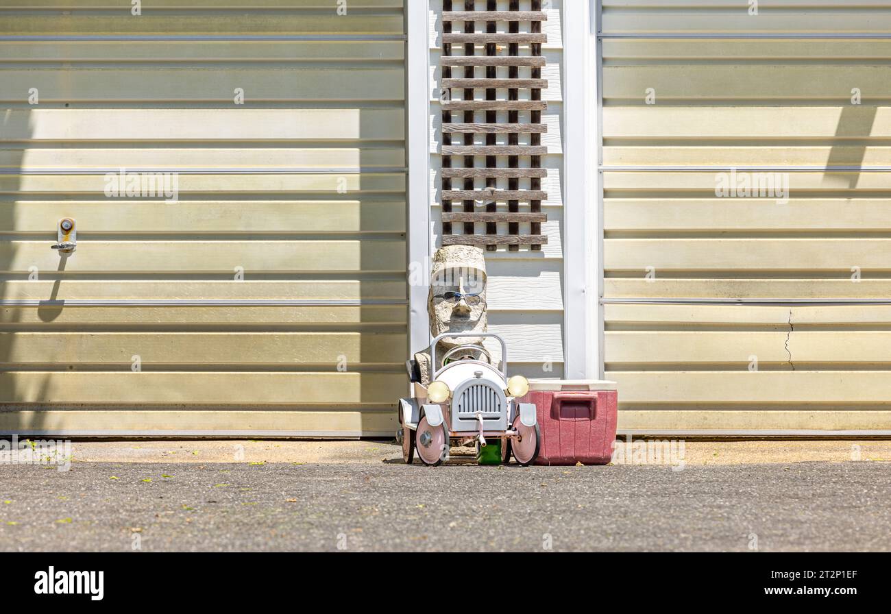 les enfants pédalent une voiture avec une tête en bois dedans Banque D'Images