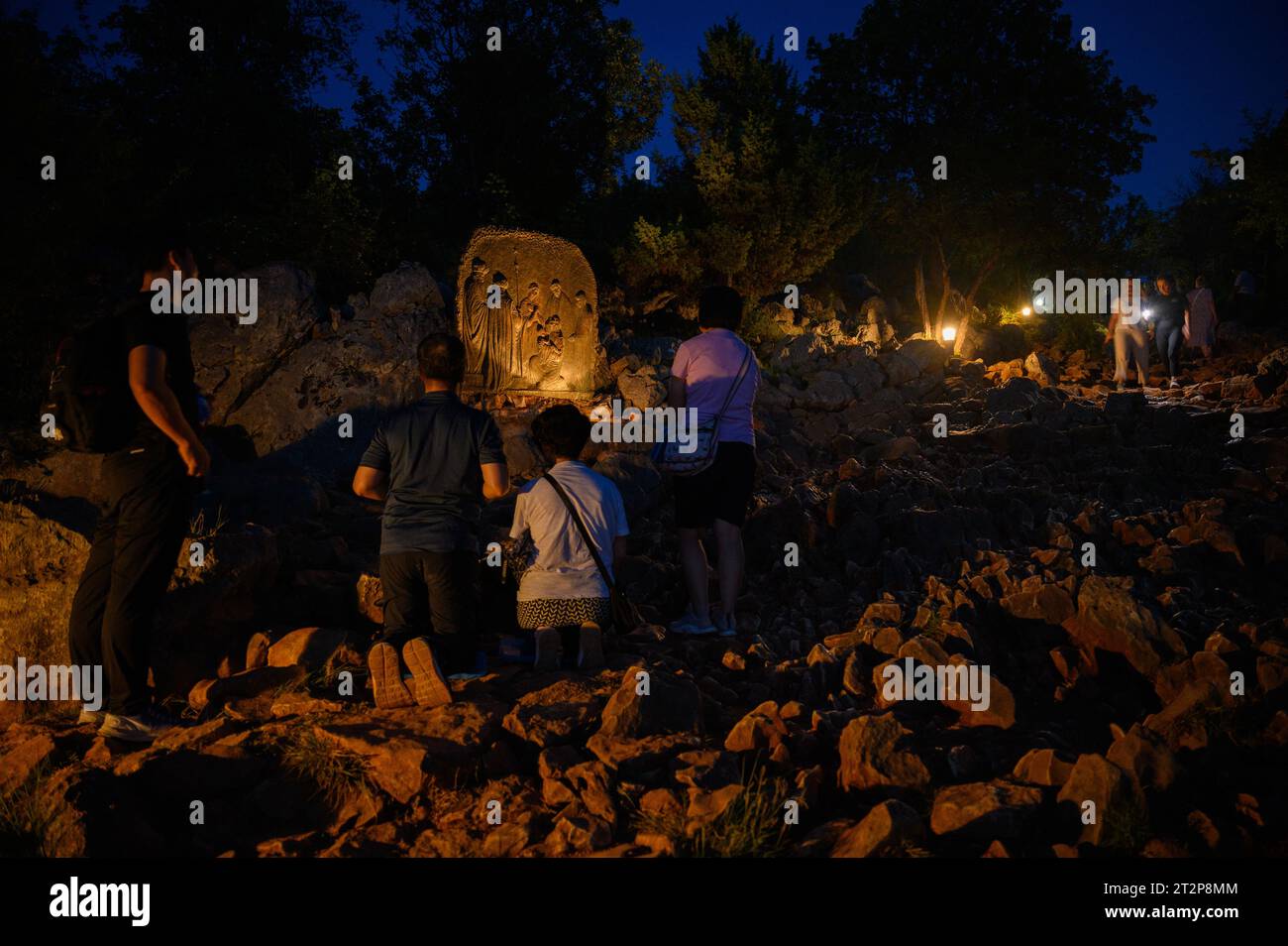 Mont Podbrdo à Medjugorje la nuit. Les gens montent et prient le rosaire. La sculpture : quatrième mystère joyeux – la Présentation de Jésus. Banque D'Images