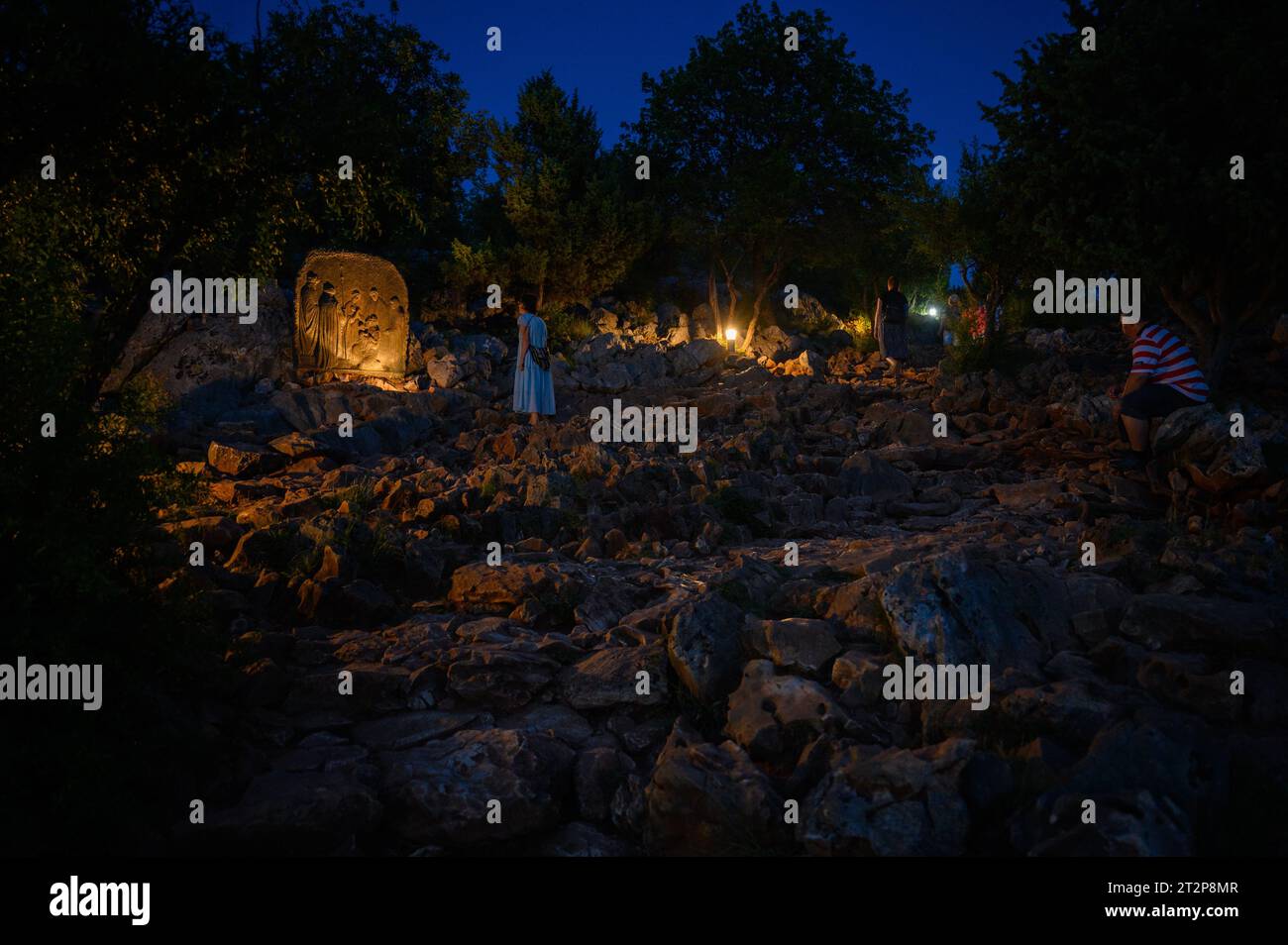 Mont Podbrdo à Medjugorje la nuit. Les gens montent et prient le rosaire. La sculpture : quatrième mystère joyeux – la Présentation de Jésus. Banque D'Images