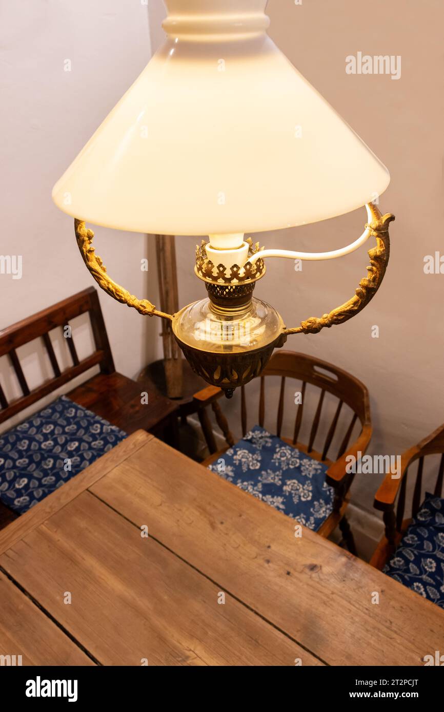Un lustre dans le style d'une vieille lampe à kérosène brille au-dessus de la table Banque D'Images