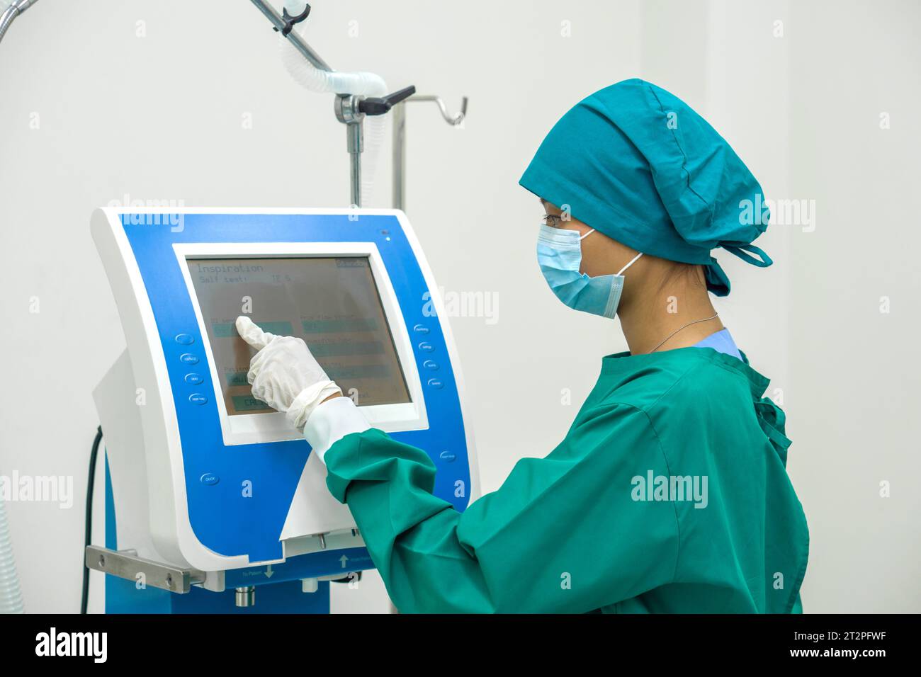 Un chirurgien inébranlable, vêtu d'une tenue chirurgicale stérile, utilise de manière experte un dispositif électronique avancé au milieu de la sérénité high-tech d'un opérat Banque D'Images