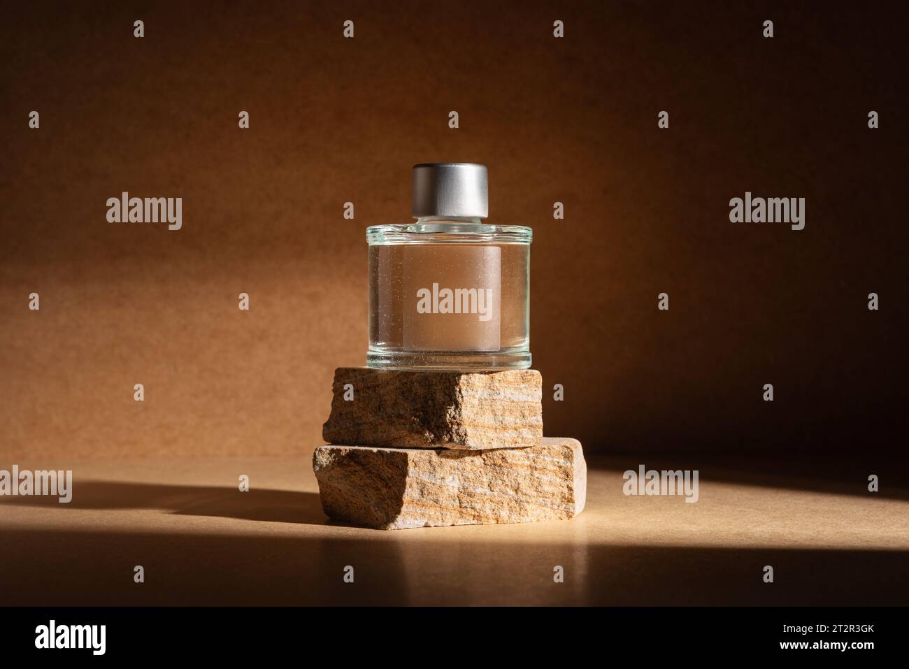 Bouteille de parfum en verre ou parfum d'intérieur sur le podium en pierre naturelle dans une lumière dramatique pour maquette et affichage du produit. Banque D'Images