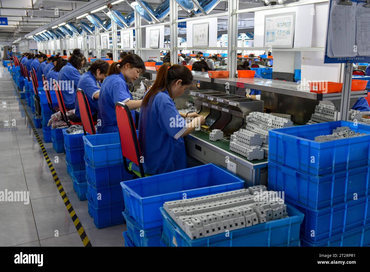Fuyang, Chine. 18 octobre 2023. Les femmes portant des combinaisons bleues travaillent sur la chaîne de montage d'une usine qui produit du matériel électrique. Le produit intérieur brut de la Chine a augmenté de 4,9 pour cent en glissement annuel au troisième trimestre, après une hausse de 6,3 pour cent au deuxième trimestre, affichant une reprise régulière malgré les pressions à la baisse, a déclaré mercredi le Bureau national des statistiques. Au cours des trois premiers trimestres, le PIB de la Chine a augmenté de 5,2 pour cent pour atteindre 91,3 billions de yuans (12,5 billions de dollars), après une croissance de 5,5 pour cent au premier semestre de l'année, a déclaré le bureau. (Image de crédit : © Sheldon Cooper/SOPA Images via Z) Banque D'Images