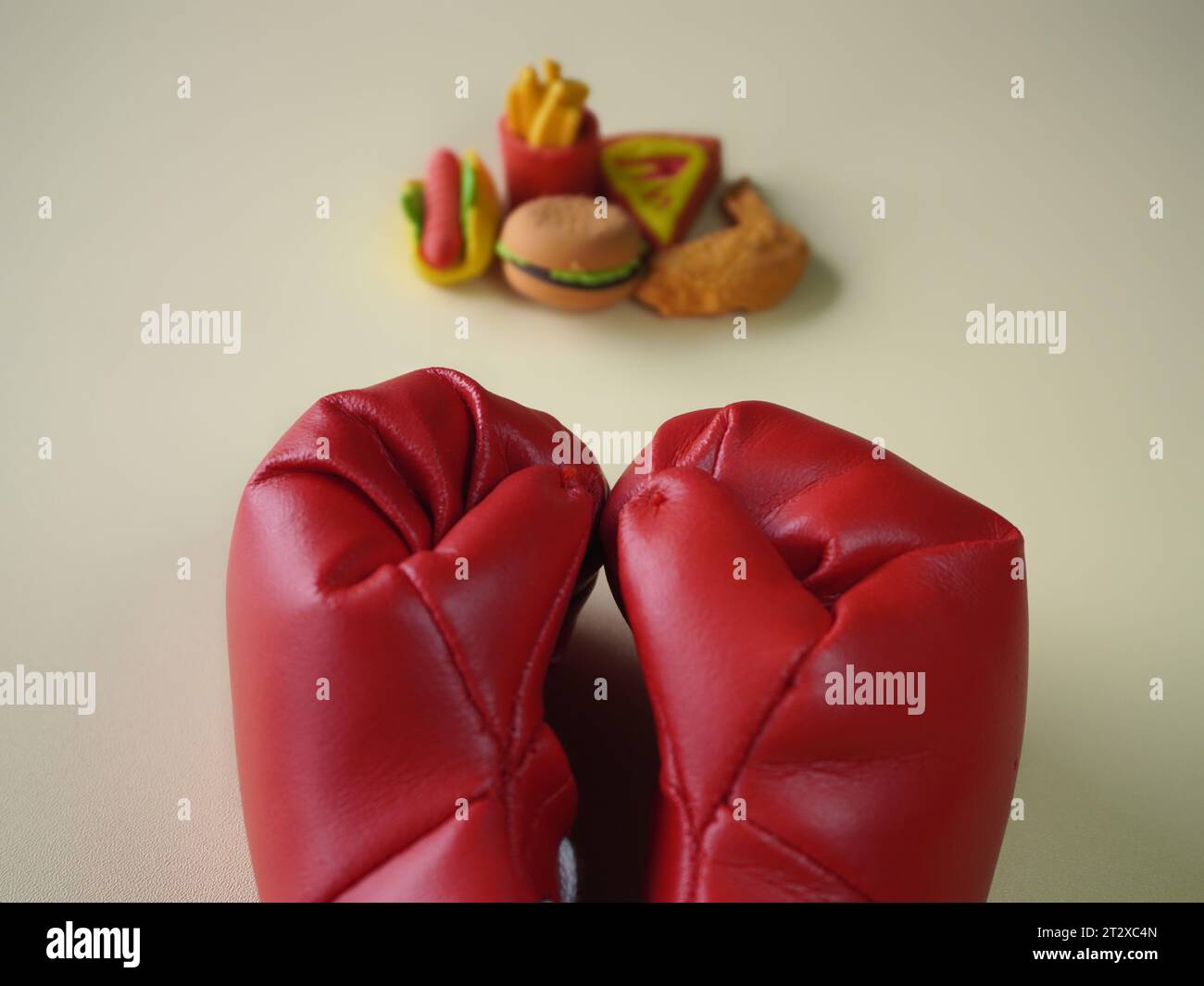 Image rapprochée de gants de boxe et de malbouffe comme des hamburgers et des frites. Concept de lutte contre les mauvaises habitudes alimentaires. Banque D'Images