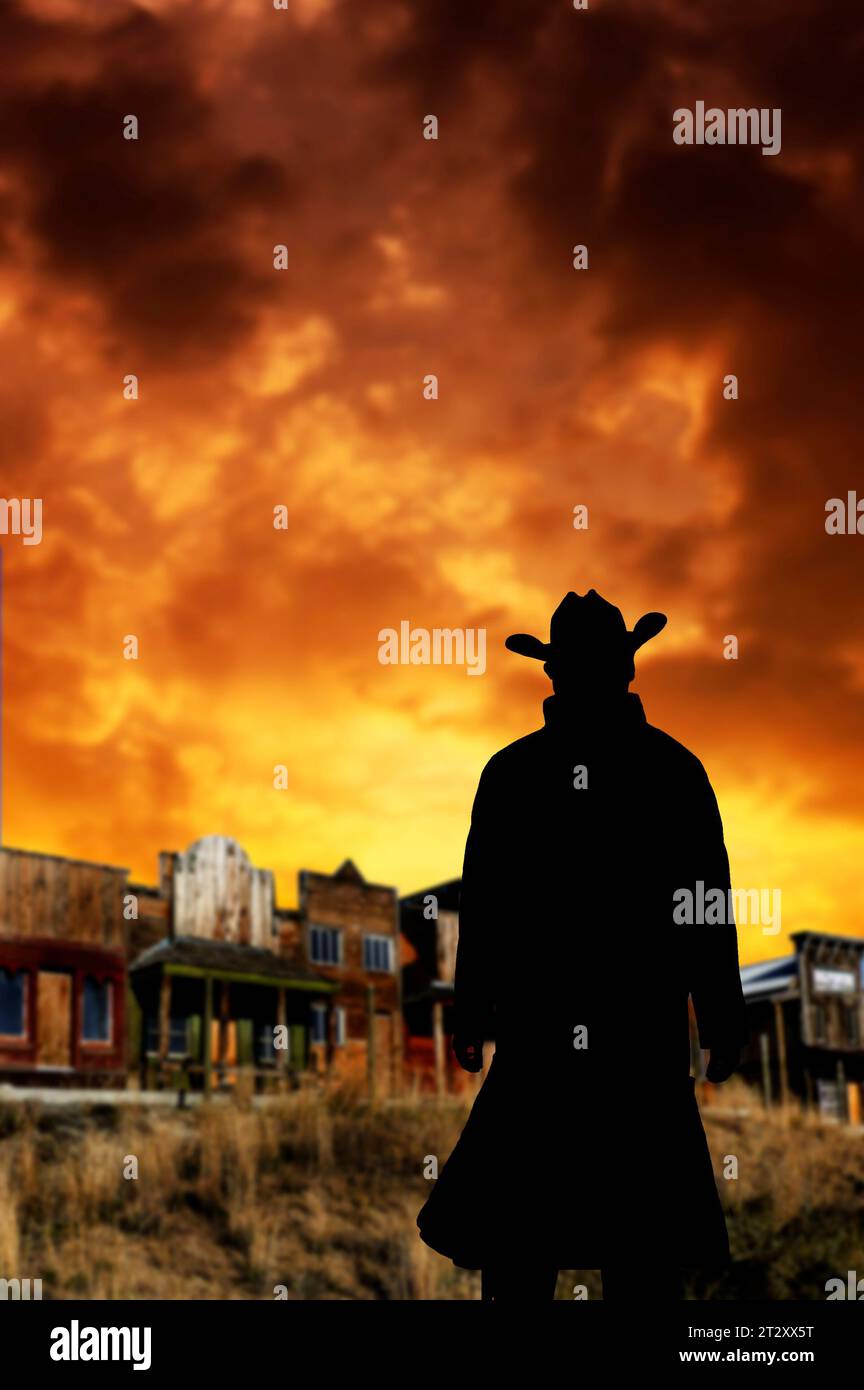 cow-boy debout une vieille ville occidentale en arrière-plan, ciel de coucher de soleil Banque D'Images
