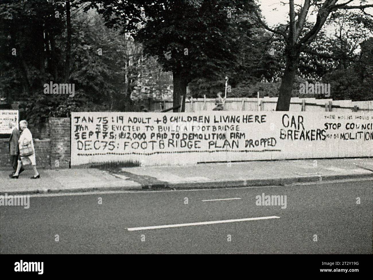 Photographie d'archives en noir et blanc des années 1970 de graffitis protestant contre la démolition d'une maison pour la fourniture d'une passerelle sur une route principale près de Brixton dans l'Inner London. Le développement de la passerelle a été annulé par la suite. Banque D'Images