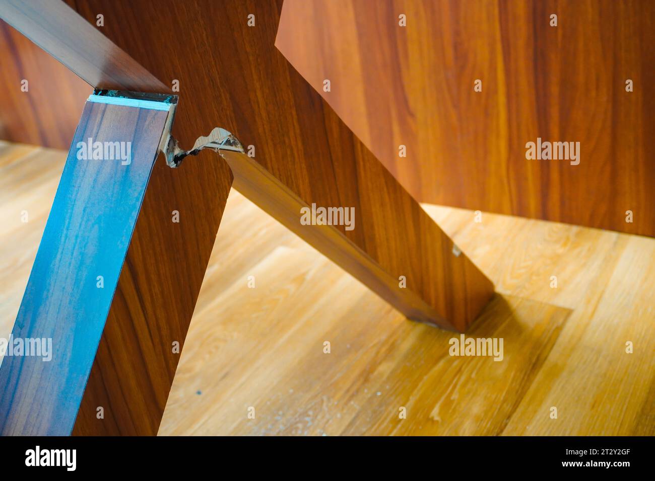 Mise au point sélective sur un pied de table en bois cassé, avec en toile de fond une planche de chaise en bois Banque D'Images