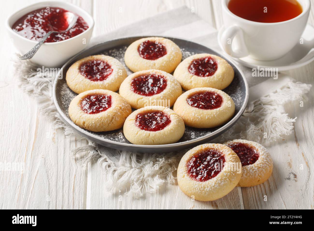 Empreinte de pouce ou Hallongrottor Swedish Raspberry Jam cookies gros plan sur l'assiette sur la table en bois blanc. Horizontal Banque D'Images