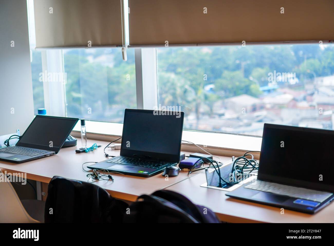 Rangée d'ordinateurs portables reposant sur le bureau devant la fenêtre après les heures de travail Banque D'Images