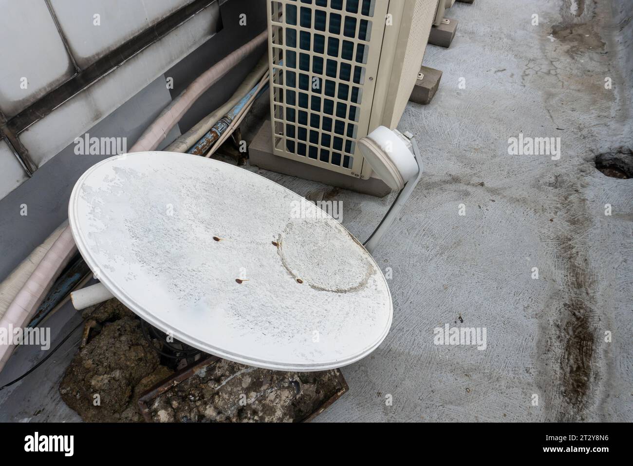 Antenne parabolique dysfonctionnelle et jetée couchée sur le sol, une métaphore visuelle de l'abandon et de la délabrement Banque D'Images