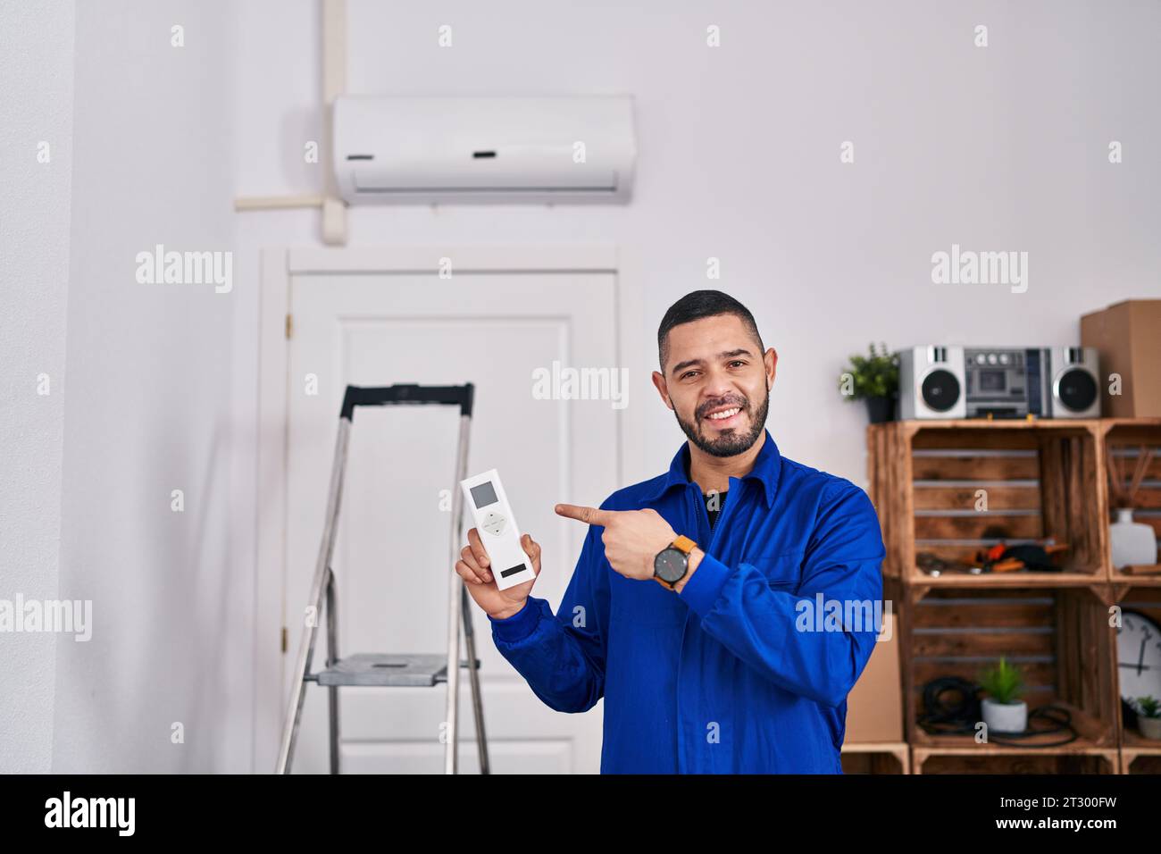 Réparateur hispanique travaillant avec climatiseur souriant heureux pointant avec la main et le doigt Banque D'Images