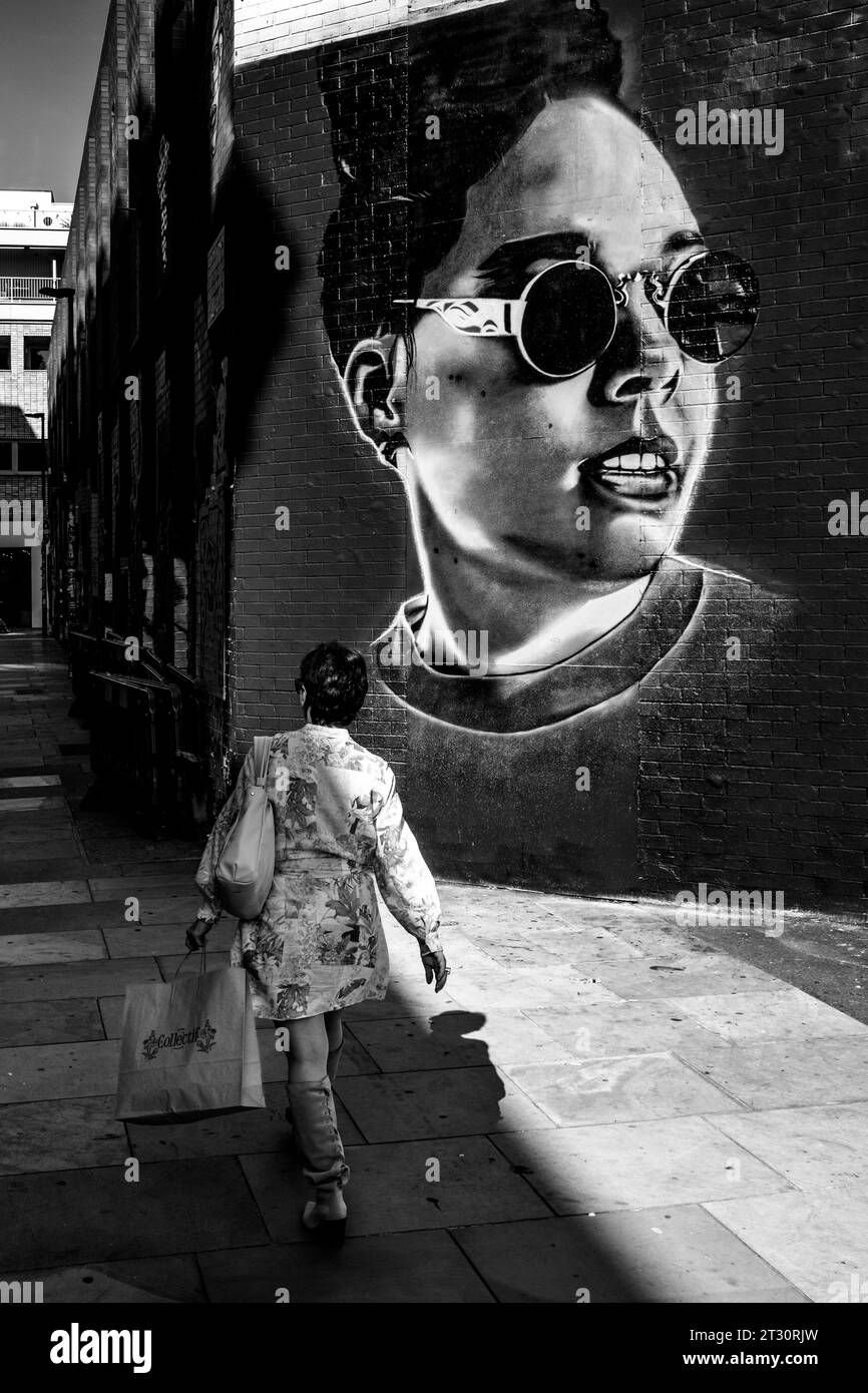 Une femme passe devant du Street Art à Shoreditch, Londres, Royaume-Uni. Banque D'Images