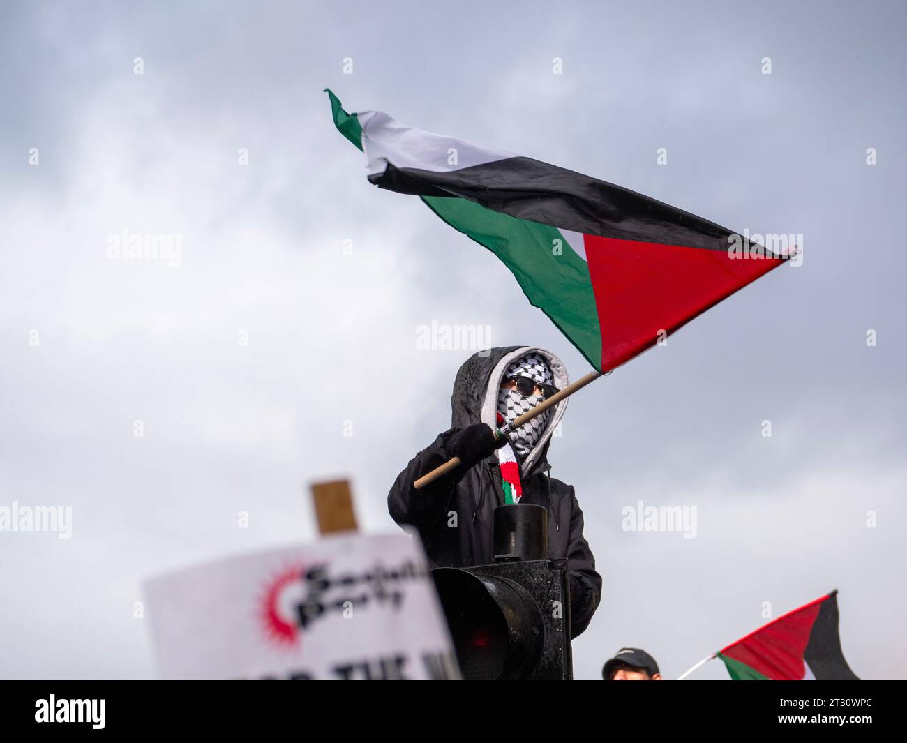 Des marcheurs pro-palestiniens à Londres, au Royaume-Uni, lors de la manifestation Marche nationale pour la Palestine Stop the war on Gaza, défilent pour protester contre le consortium Israël Palestine sur la bande de Gaza. Manifestant assis au feu de circulation avec masque couvrant le visage, drapeau flottant de la Palestine Banque D'Images