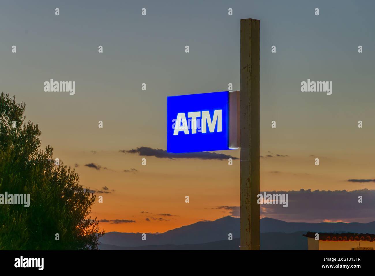 Panneau GAB phosphorescent. Lettres blanches sur fond bleu. Le ciel ci-dessous est illuminé par le soleil couchant. coucher du soleil nuit obscurité argent argent argent argent argent Banque D'Images