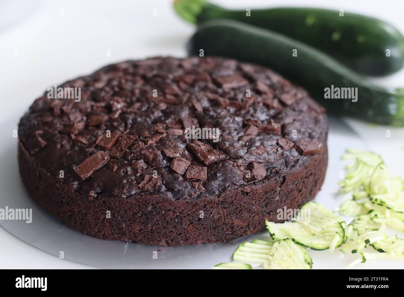 Gâteau au chocolat courgettes de forme ronde. Gâteau au chocolat double humide avec courgettes râpées, poudre de coco, chocolat et pépites de chocolat. Tiré sur fond blanc Banque D'Images