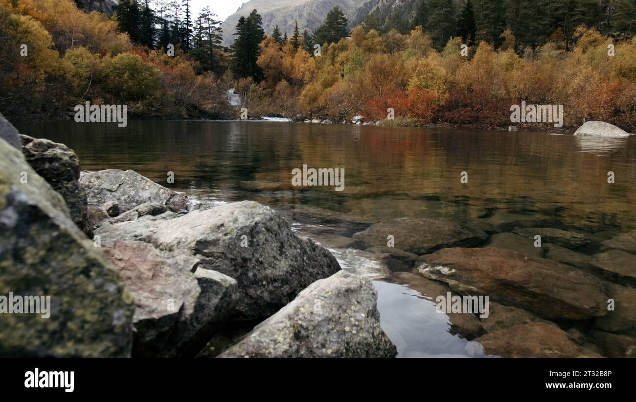 Grand lac magnifique avec des arbres verts et jaunes et de grosses pierres sur la rive. Créatif. Incroyable eau transparente propre. Banque D'Images