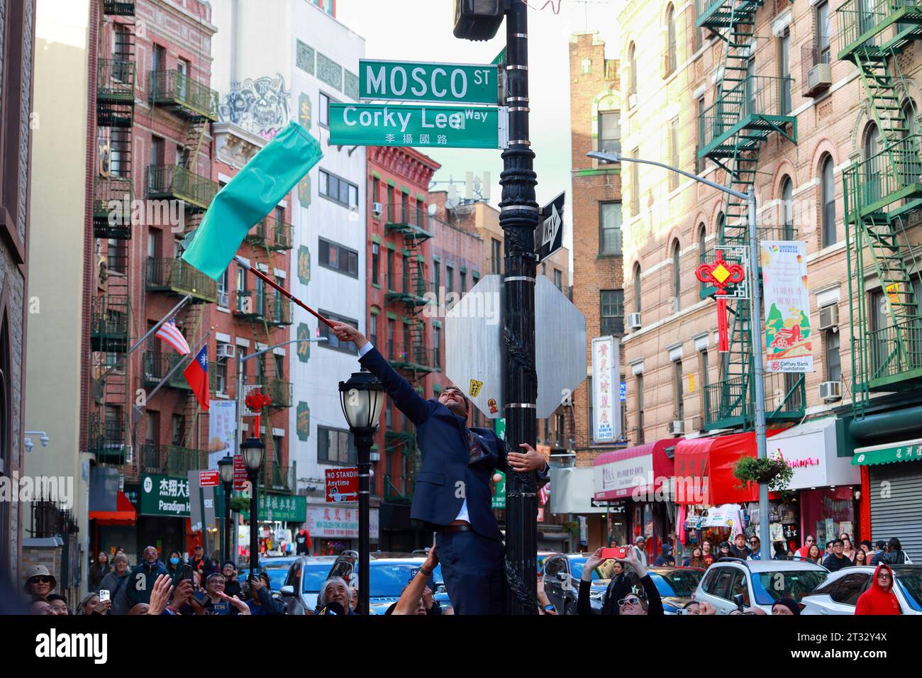 22 octobre 2023, New York. Les gens célèbrent Corky Lee Way 李揚國路 co-nommer Mosco St dans le quartier chinois de Manhattan. Chris Marte, membre du Conseil de New York, grimpe sur un lampadaire pour révéler le nouveau panneau. Corky Lee était un photojournaliste, photographe et militant des droits civiques qui a documenté l'histoire de l'Amérique asiatique ; il est parfois appelé le « photographe lauréat non officiel d'Amérique asiatique ». M. Lee est décédé en 2021 de complications dues au Covid-19. Banque D'Images