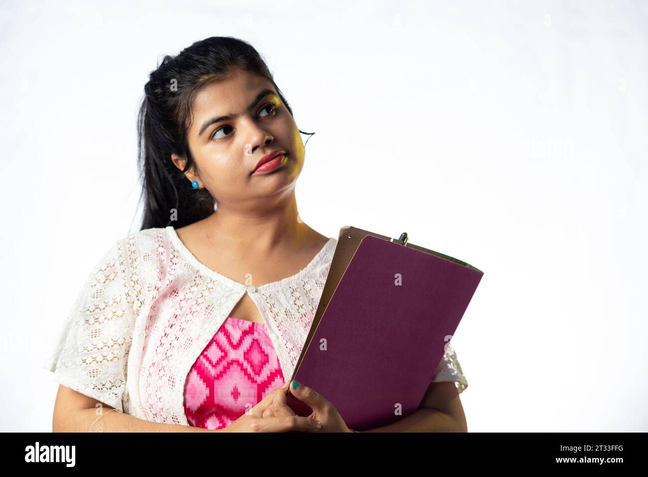 Une jolie jeune fille indienne pensant et regardant de côté sur fond blanc Banque D'Images