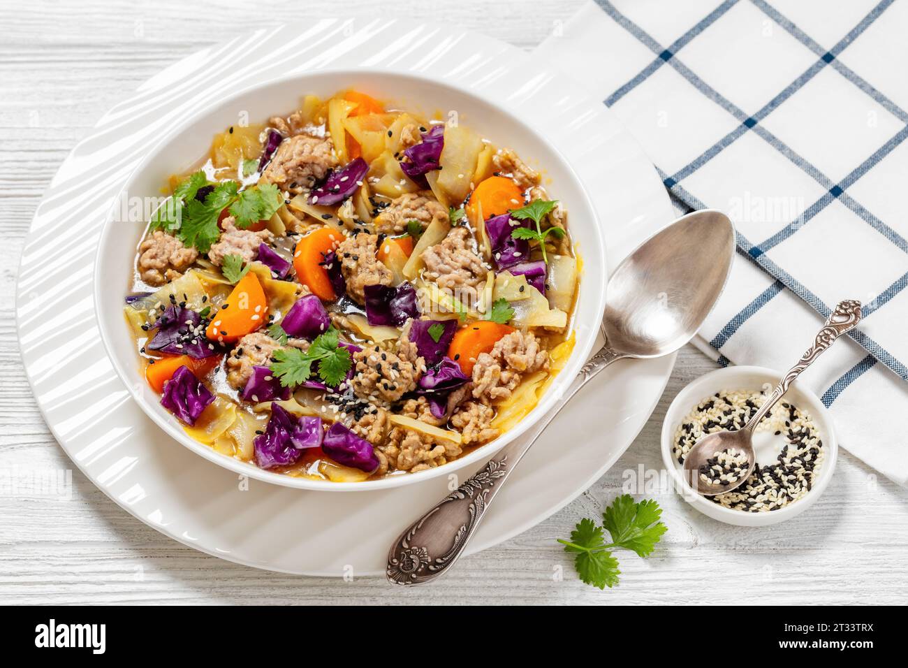 soupe au chou roulé aux œufs avec du porc haché et des légumes dans un bol blanc sur une table en bois blanc avec ispon, cuisine asiatique, vue horizontale, gros plan Banque D'Images