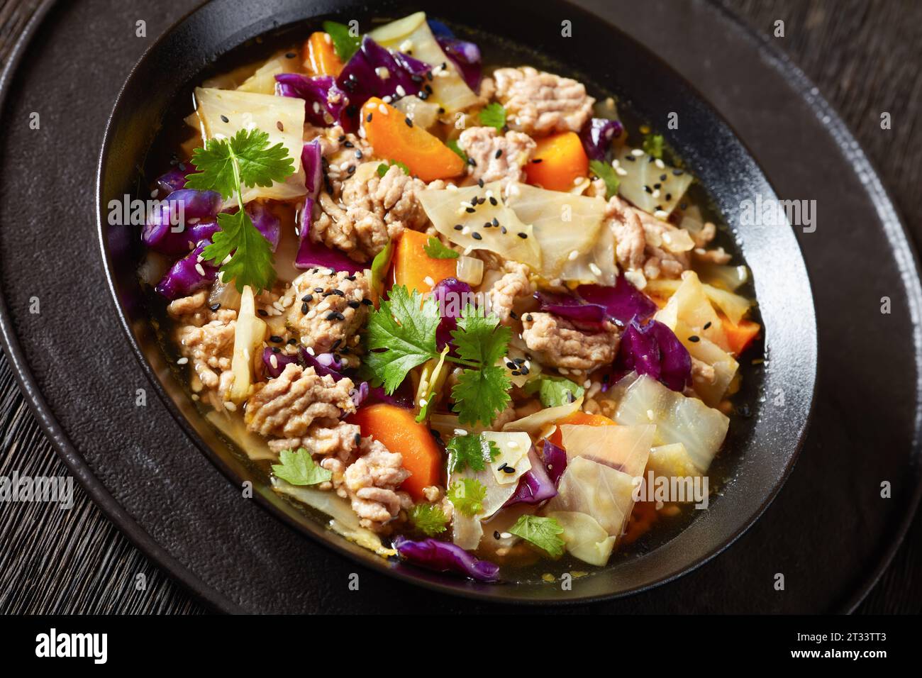 soupe au chou roulé aux œufs avec du porc haché et des légumes dans un bol noir sur une table en bois sombre, cuisine asiatique, gros plan Banque D'Images