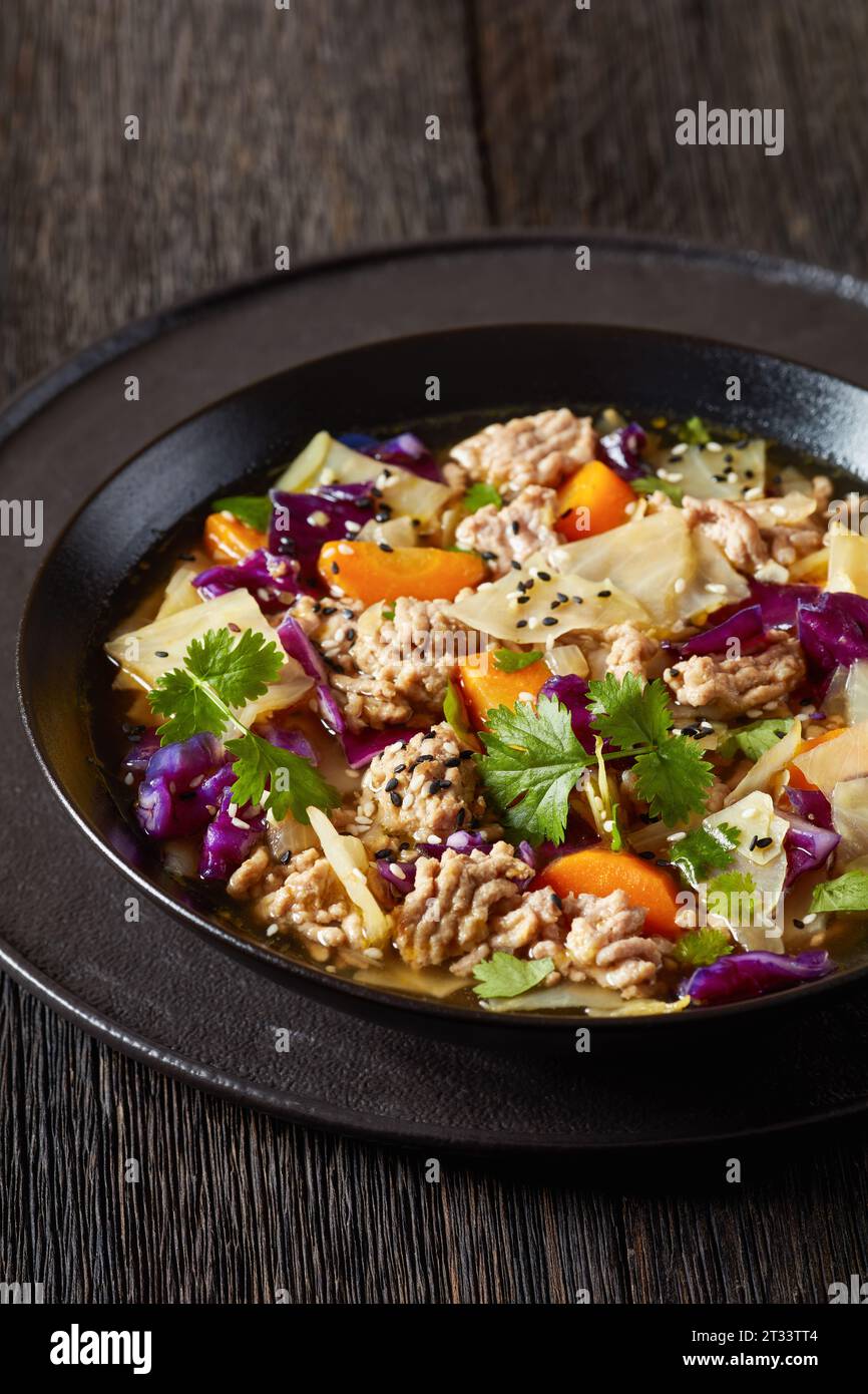 soupe au chou roulé aux œufs avec du porc haché et des légumes dans un bol noir sur une table en bois sombre, cuisine asiatique, vue verticale d'en haut, gros plan Banque D'Images