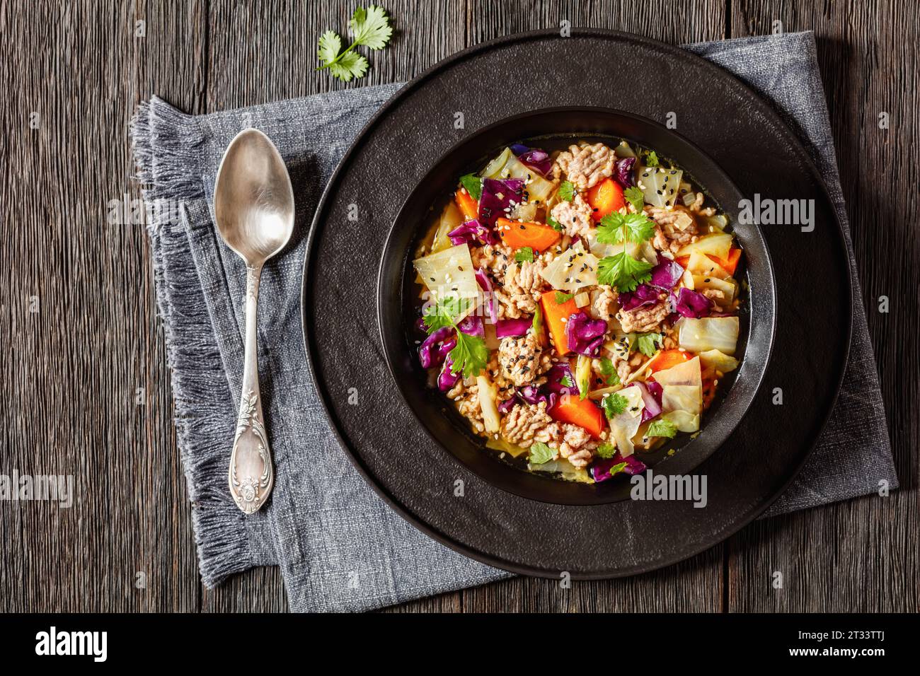 soupe au chou roulé aux œufs avec du porc haché et des légumes dans un bol noir sur une table en bois sombre avec cuillère, cuisine asiatique, vue horizontale d'en haut, plat l Banque D'Images