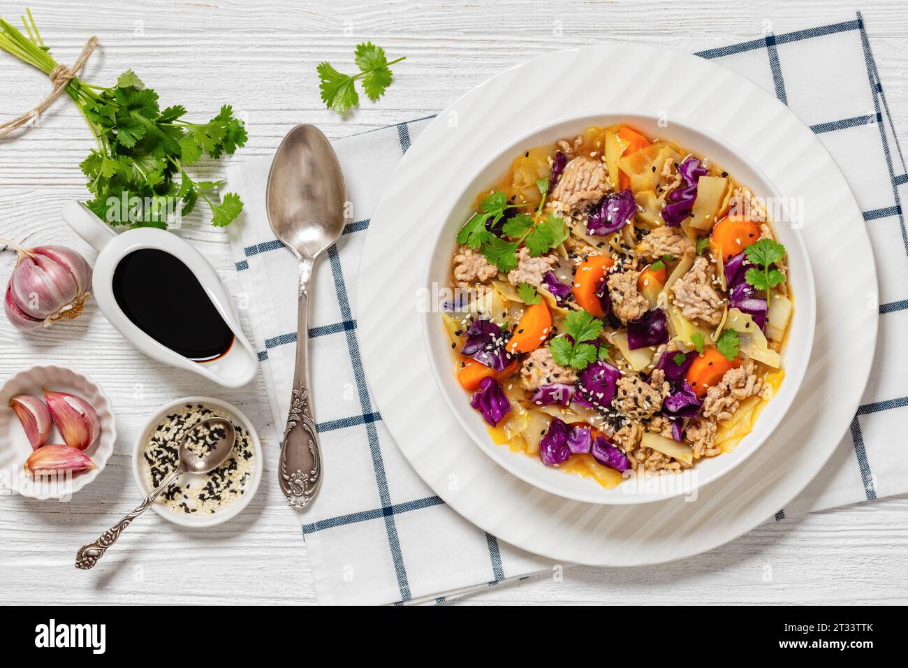 soupe de chou roulé d'oeufs avec du porc haché et des légumes dans un bol blanc sur une table en bois blanc avec des ingrédients, cuisine asiatique, vue horizontale d'en haut, Banque D'Images