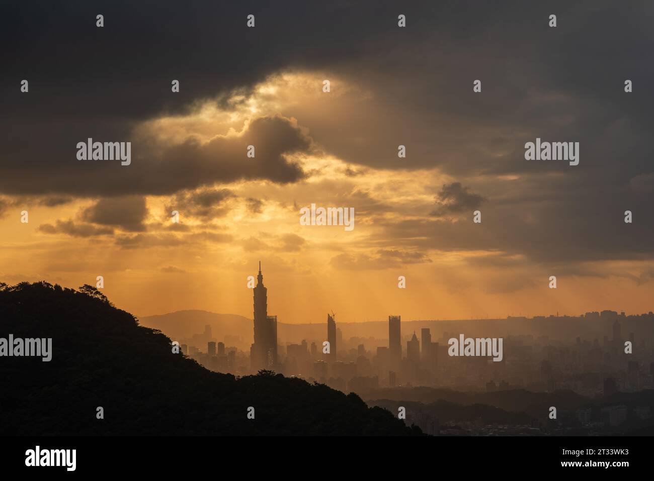 Au crépuscule, le soleil traverse les nuages et brille sur la ville de Taipei. Silhouettes de bâtiments urbains. Ciel orange et nuages sombres. Banque D'Images