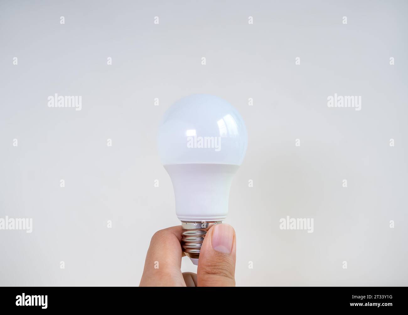Ampoule LED blanche moderne ou ou lampe d'économie tenant à la main isolée sur fond blanc. Recycler l'énergie et la créativité des concepts de pensée d'idée Banque D'Images