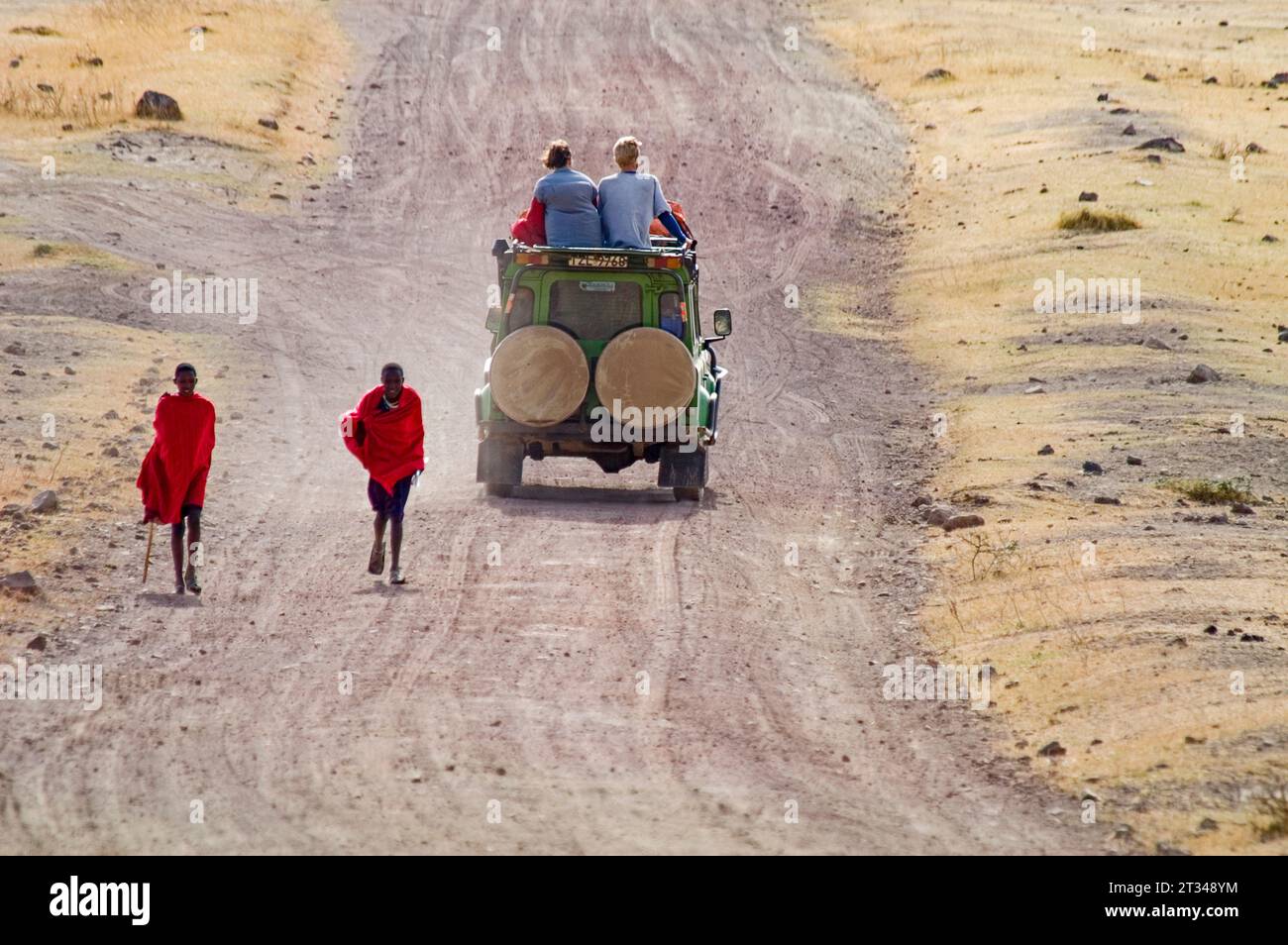Masai adolescents marchant devant des touristes occidentaux sur Safari dans le parc national de Ngorngoro, Tanzanie Banque D'Images