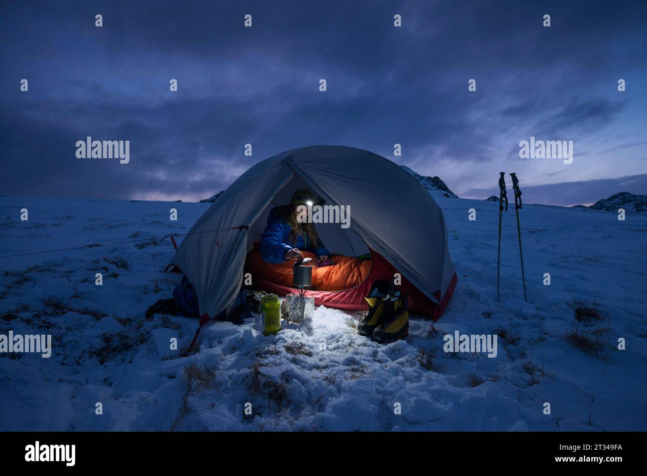Femme campant dans la tente la nuit, Vestvagoya, Lofoten, Norvège Banque D'Images
