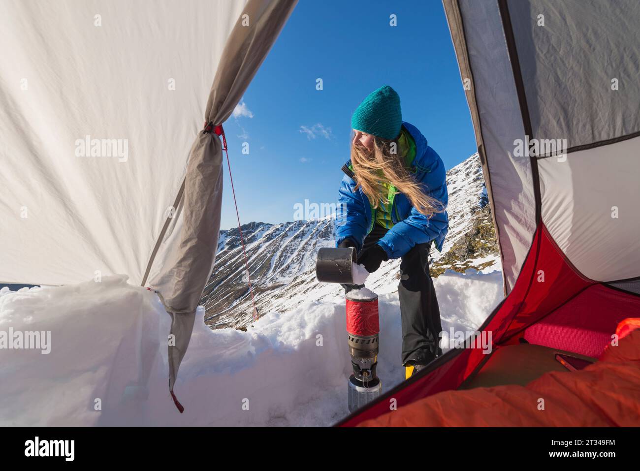 Randonneuse faisant fondre la neige en camping, Moskenesoya, Lofoten, Norvège Banque D'Images