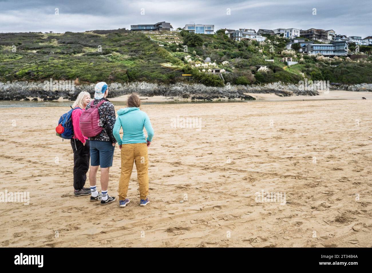 Trois visiteurs debout sur Crantock Beach regardant vers le haut de la propriété sur entier à Newquay en Cornouailles au Royaume-Uni. Banque D'Images