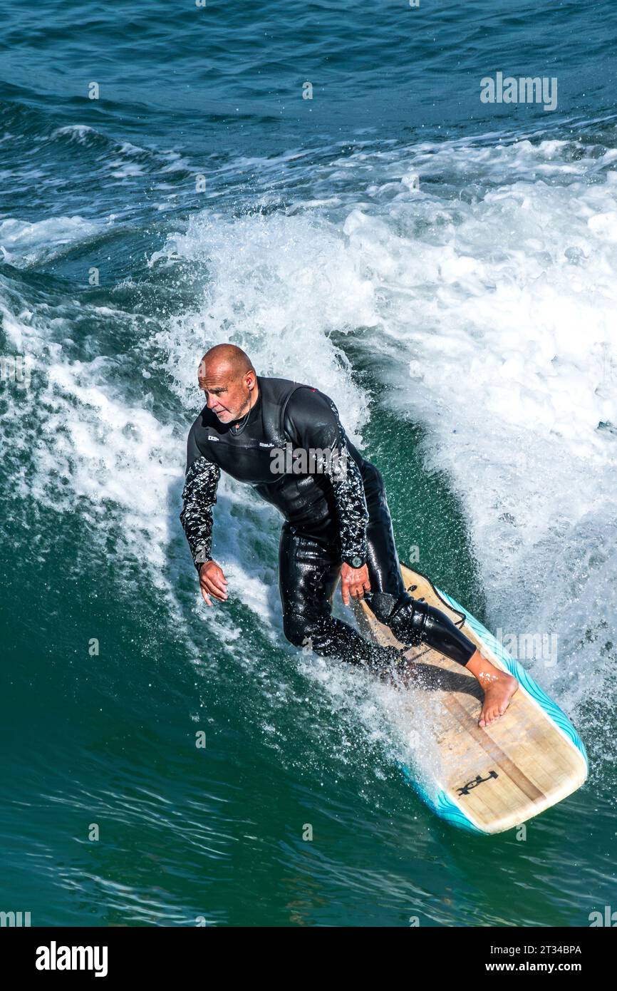 Un surfeur mature chevauchant une vague à Great Western à Newquay en Cornouailles au Royaume-Uni. Banque D'Images