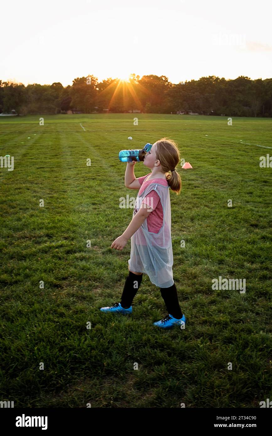 Jeune fille prenant une pause d'eau après la pratique de football Banque D'Images