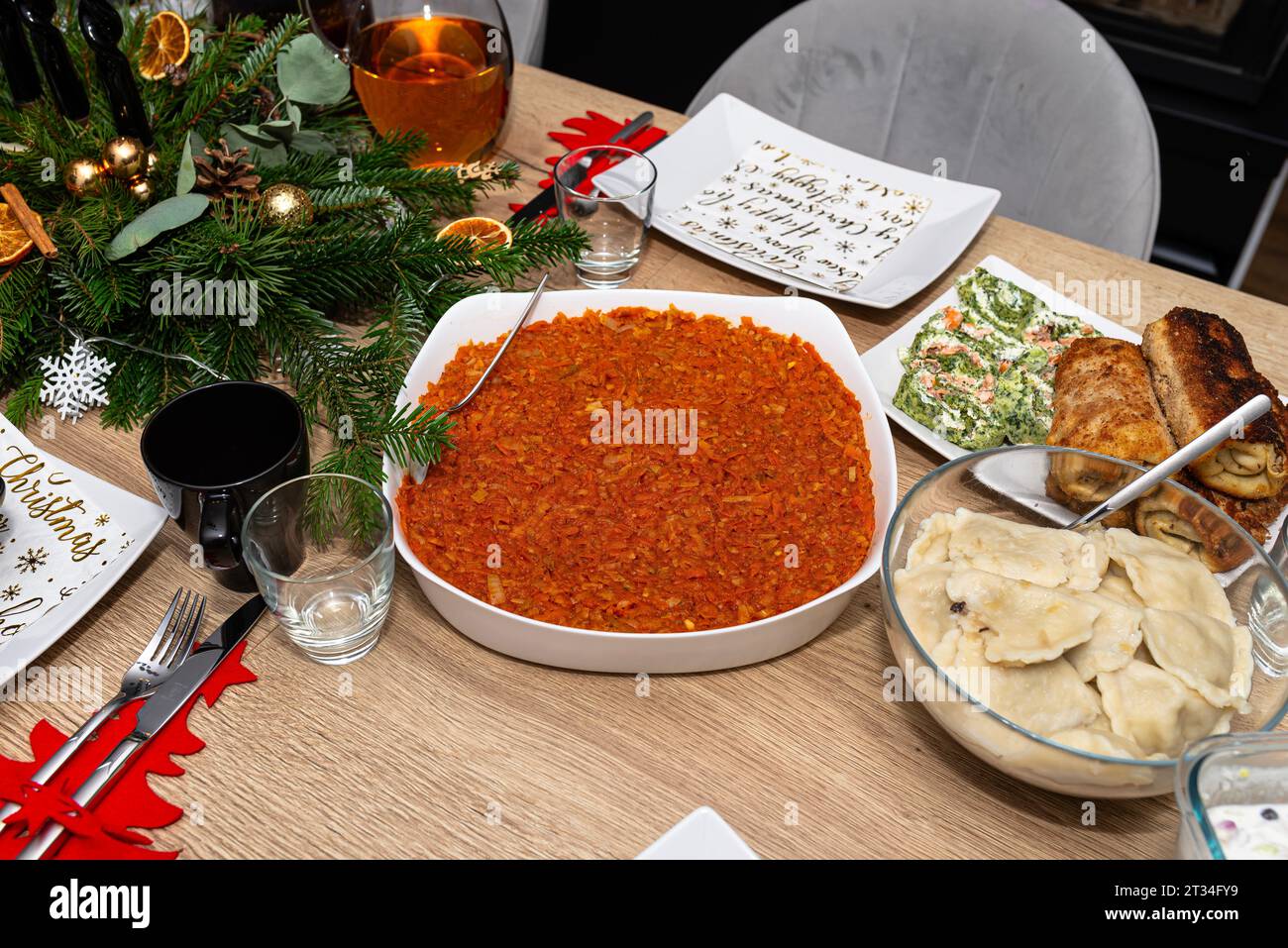La table est mise avant le dîner de Noël en Pologne, avec des filets de poisson cuits dans une salade de carottes, des boulettes et des croquettes visibles. Banque D'Images