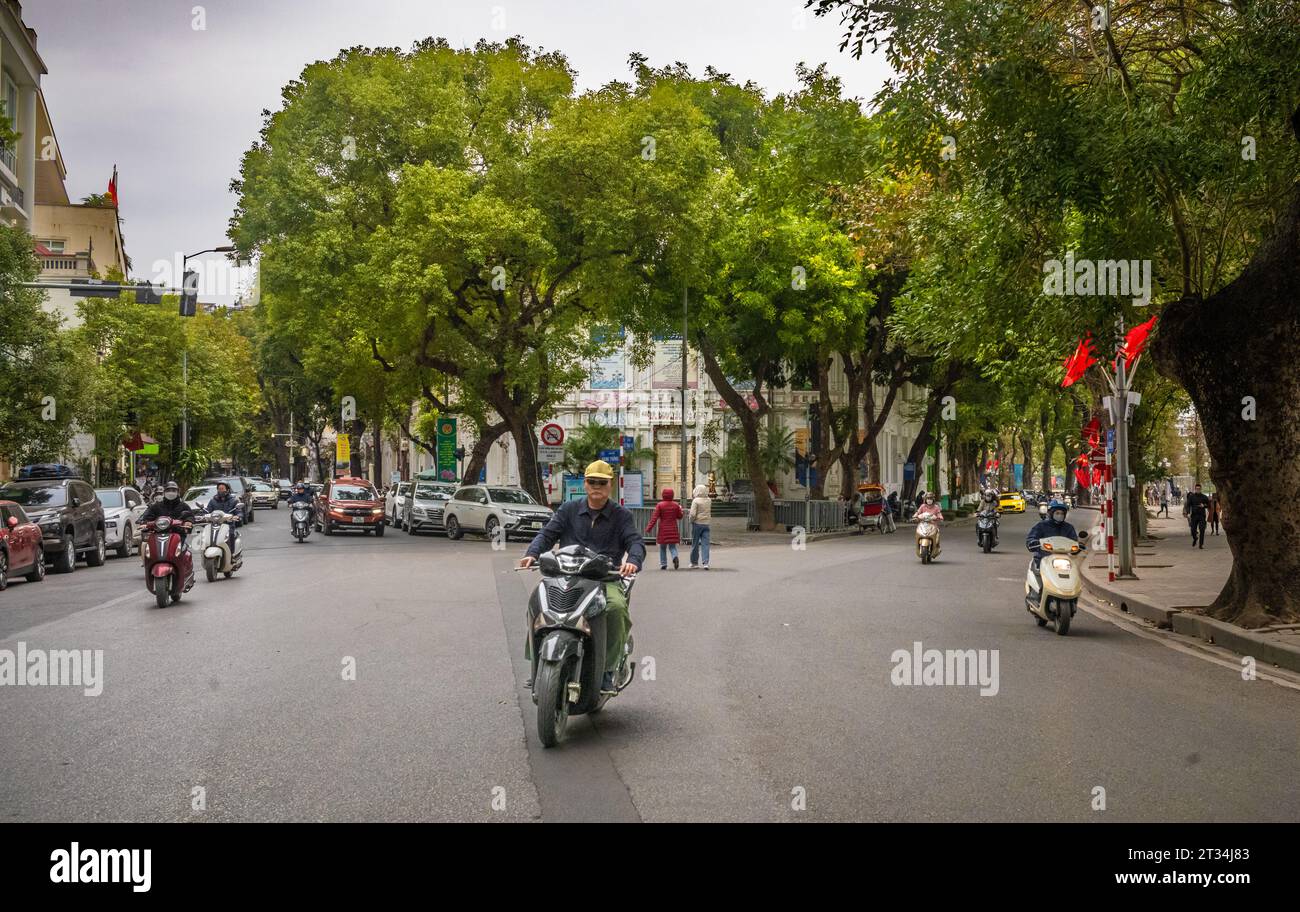 Un Vietnamien conduit sa moto le long de le Thai pour flâner par une journée d'hiver nuageuse dans le centre de Hanoi, Vietnam. Banque D'Images
