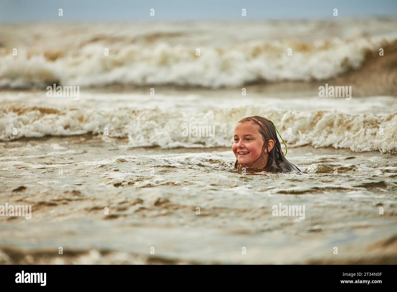 Petite fille jouant avec les vagues dans la mer. Gamin éclaboussant de manière ludique dans les vagues. Enfant sautant en mer. Vacances sur la plage. Éclaboussures d'eau. Fun et pla Banque D'Images