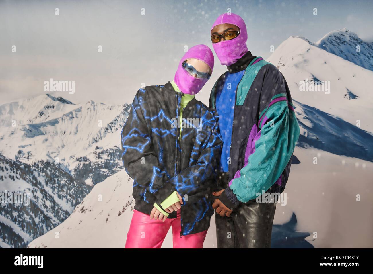 couple élégant dans une tenue lumineuse vibrante avec lunettes de soleil avec toile de fond de montagne, concept d'hiver Banque D'Images