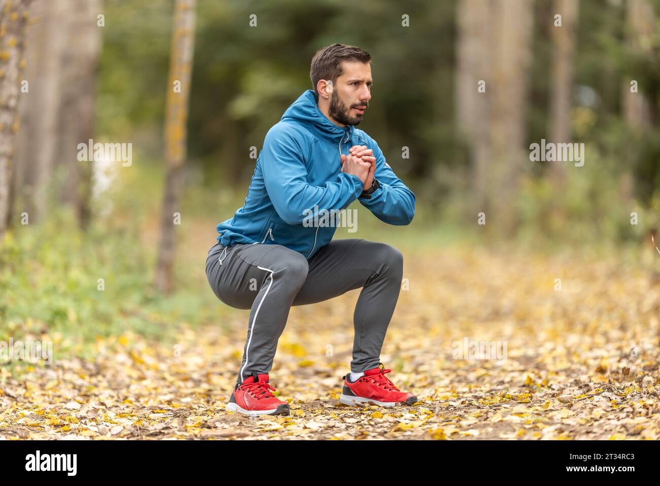 Un jeune athlète s’réchauffe avant de courir s’entraîner dans le parc. Il réchauffe la partie inférieure du corps. Banque D'Images