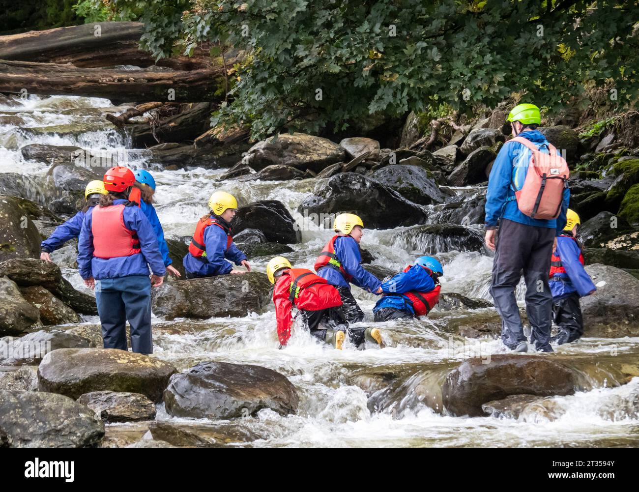 Un groupe d'enfants en voyage d'aventure, explorant la rivière à Tilberthwaite près de Coniston, Lake District, Royaume-Uni Banque D'Images
