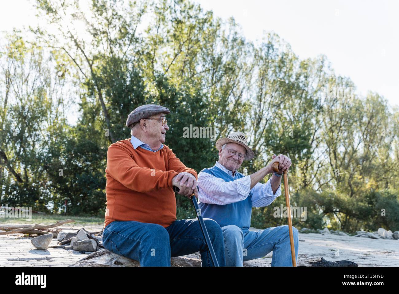Deux vieux amis assis sur un tronc d'arbre par le partage de souvenirs, riverside Banque D'Images