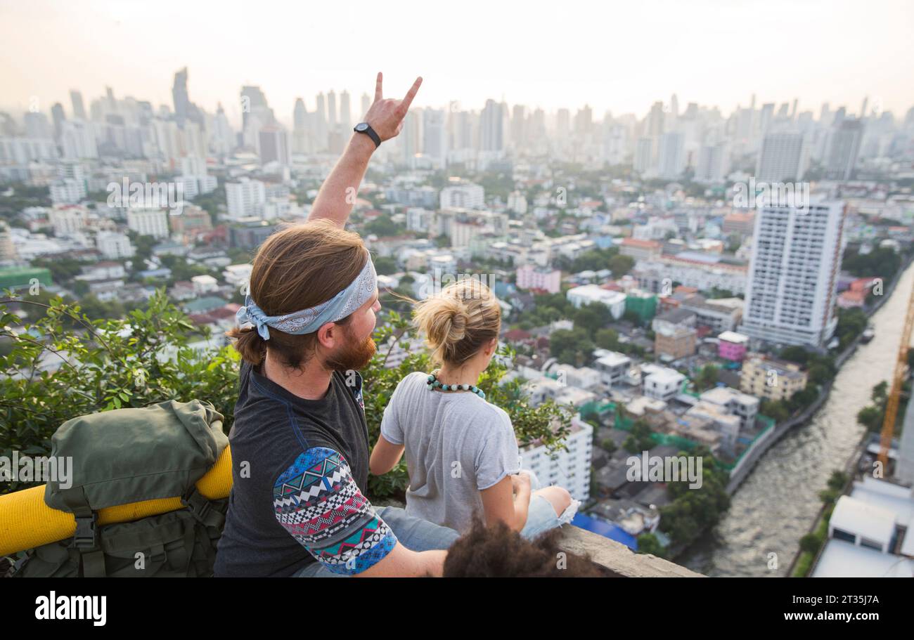 Homme faisant signe de corne avec femme regardant la vue de la ville depuis le toit Banque D'Images