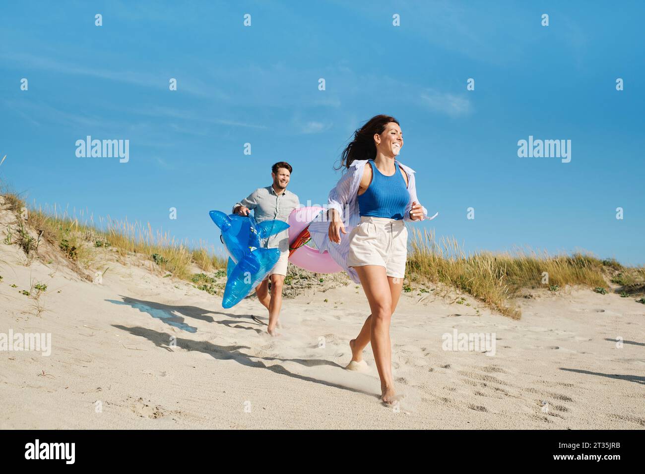 Femme heureuse avec homme courant à la plage le jour ensoleillé Banque D'Images