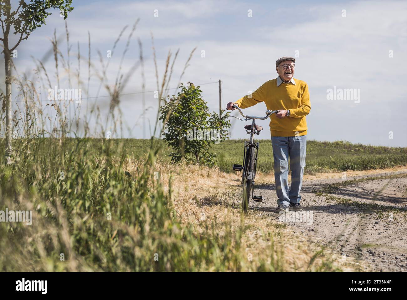 Heureux homme âgé marchant avec le vélo sur la route Banque D'Images