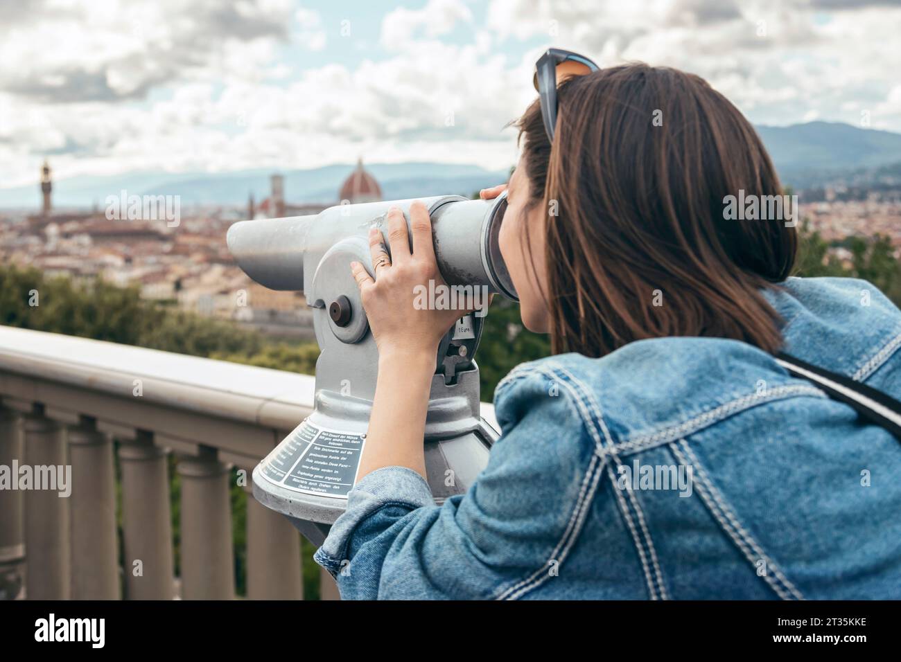 Femme regardant à travers des jumelles debout à la balustrade Banque D'Images